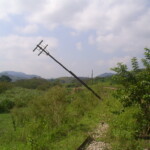 Poste caindo às margens da ferrovia
