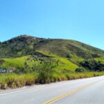 Trecho de rodovia onde se pode visualizar o leito ferroviário nos morros